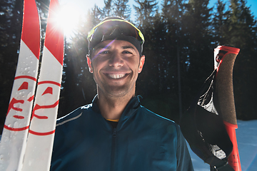 Image showing Portrait handsome male athlete with cross country skis in hands and goggles, training in snowy forest. Healthy winter lifestyle concept.