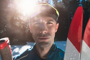 Image showing Portrait handsome male athlete with cross country skis in hands and goggles, training in snowy forest. Healthy winter lifestyle concept.