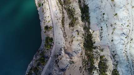 Image showing Turquoise water in a mountain forest lake with pine trees. Aerial view of blue lake and green forests. View on the lake between mountain forest. Over crystal clear mountain lake water. Fresh water