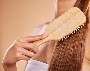 Image showing Hairbrush, hair care and woman brushing her hair in a studio for wellness, health and self care. Cosmetic, beauty and closeup of a female model doing a hairstyle or combing knots by brown background.