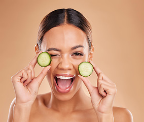 Image showing Skincare, wink and portrait of woman with cucumber in hands for wellness, facial treatment and natural cosmetics. Beauty, spa and happy girl with fruit for detox, vitamin c and healthy skin in studio