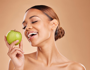 Image showing Beauty, skincare and woman with apple, healthy lifestyle and happiness against a brown studio background. Female, lady and fruit for diet, smile and cosmetics with treatment, smooth and soft skin