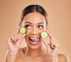 Image showing Skincare, holding cucumber and face of woman with smile for wellness, facial treatment and natural cosmetics. Beauty, spa aesthetic and happy girl with fruit for detox, vitamin c and health in studio