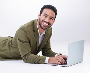 Image showing Happy, laptop and portrait of a man in studio relaxing while typing on a keyboard doing research. Happiness, smile and Indian male model with computer working on project isolated by white background.