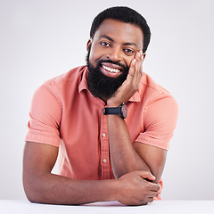 Image showing Happy, handsome and portrait of a black man leaning on a table isolated on a white background. Smile, relax and an African guy looking relaxed, calm and at peace with confidence on a studio backdrop