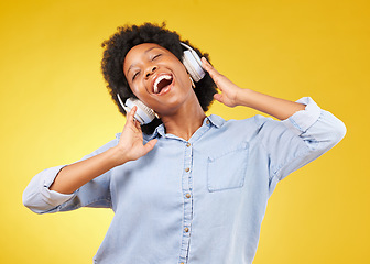 Image showing Black woman, headphones and freedom, listening to music and happiness with dance on yellow studio background. Happy female, carefree and sing along to radio, audio streaming with fun and technology