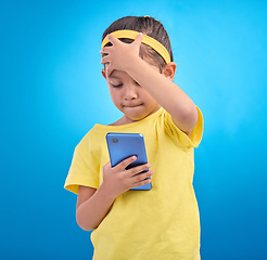 Image showing Phone, face palm and a girl on a blue background in studio reading a text message or post on social media. Contact, mobile and mistake with a young female child looking at bad news on her smartphone