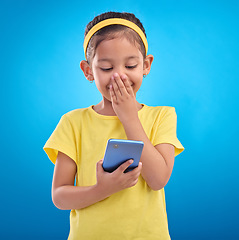 Image showing Phone, smile and child laugh on blue background for social media, funny video and internet meme in studio. Technology, communication mockup and happy girl with humor, joke and online on smartphone