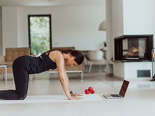 Image showing Young Beautiful Female Exercising, Stretching and Practising Yoga with Trainer via Video Call Conference in Bright Sunny House. Healthy Lifestyle, Wellbeing and Mindfulness Concept.