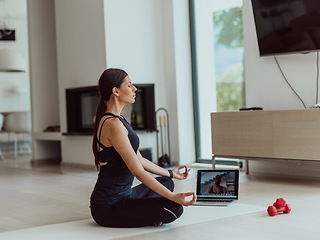 Image showing Young Beautiful Female Exercising, Stretching and Practising Yoga with Trainer via Video Call Conference in Bright Sunny House. Healthy Lifestyle, Wellbeing and Mindfulness Concept.