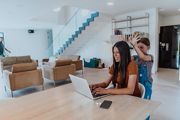 Image showing Mother with her daughter talking on laptop with family and friends while sitting in modern living room of big house