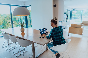 Image showing Woman sitting in living room using laptop look at cam talk by video call with business friend relatives, head shot. Job interview answering questions.