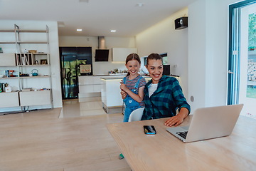 Image showing Mother with her daughter talking on laptop with family and friends while sitting in modern living room of big house