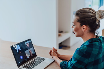 Image showing Woman sitting in living room using laptop look at cam talk by video call with business friend relatives, head shot. Job interview answering questions.