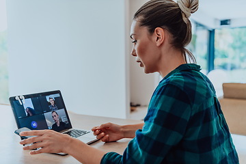 Image showing Woman sitting in living room using laptop look at cam talk by video call with business friend relatives, head shot. Job interview answering questions.