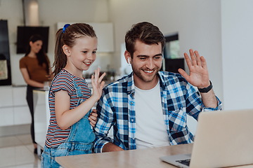 Image showing Father and daughter in modern house talking together on laptop with their family during holidays. The life of a modern family