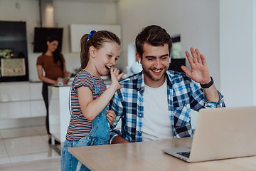 Image showing Father and daughter in modern house talking together on laptop with their family during holidays. The life of a modern family