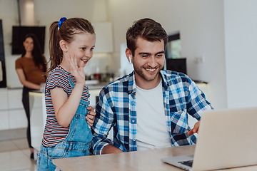 Image showing Father and daughter in modern house talking together on laptop with their family during holidays. The life of a modern family