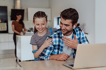 Image showing Father and daughter in modern house talking together on laptop with their family during holidays. The life of a modern family