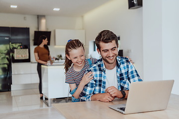 Image showing Father and daughter in modern house talking together on laptop with their family during holidays. The life of a modern family