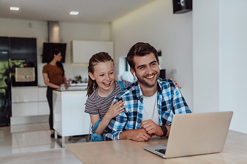 Image showing Father and daughter in modern house talking together on laptop with their family during holidays. The life of a modern family