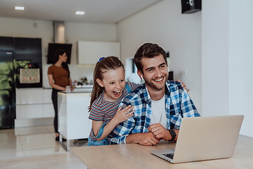 Image showing Father and daughter in modern house talking together on laptop with their family during holidays. The life of a modern family