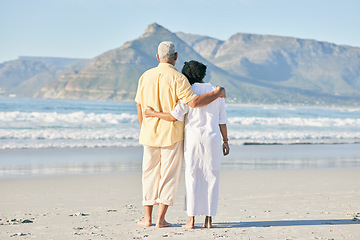 Image showing Old couple at beach, hug and travel with retirement and love outdoor, vacation with ocean view and relax in nature. Peace, zen and tropical island, man and woman watching sea waves, back and wellness