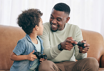 Image showing Black family, father and child playing video games on living room sofa together with controllers at home. Happy African American dad with son with smile enjoying bonding time on console entertainment