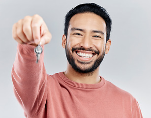 Image showing Key, real estate and smile with portrait of man in studio and giving you property, new homeowner or achievement. Rent, pride and purchase with male on white background for house, tenant or investment