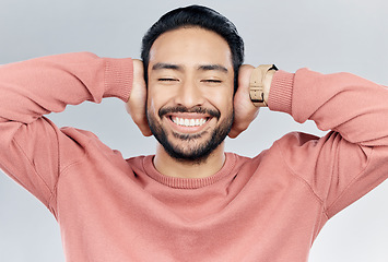 Image showing Face, happy and silence with a man in studio on a gray background to cover his ears while enjoying quiet. Noise, smile and relax with a handsome young male blocking sounds with his hands for peace