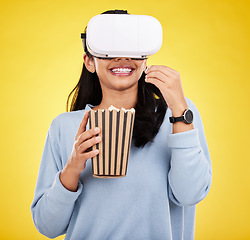 Image showing Woman is eating popcorn, happy and VR goggles with snack for watching tv or movie on yellow studio background. Future technology, female with virtual reality experience and corn treat, cinema and UX