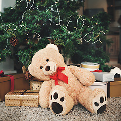 Image showing Christmas, gift and festive with a teddy bear by a tree, ready for celebration during the holiday season. December, event and a stuffed animal sitting in the living room of an apartment as a present