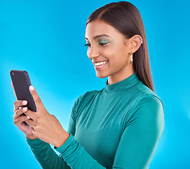 Image showing Woman, smile and typing on phone in studio for communication, social media or mobile app. Gen z model person with beauty and smartphone in hands on blue background for network connection or internet