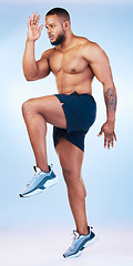 Image showing Bodybuilder man, studio and training for running, explosive and balance with focus by blue background. Young fitness expert, body wellness and jumping for strong legs, muscle and health by backdrop