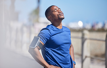 Image showing Fitness, training and tired man runner outdoors for break from exercise, cardio or running on blurred background. Workout, stop and breathe by athletic male outside for marathon, run or sport routine