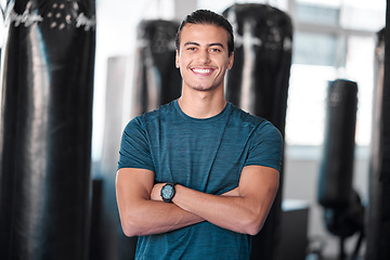 Image showing Portrait, punching bag with a man boxer in the gym, standing arms crossed for fitness or motivation. Happy, exercise and confidence with a handsome young male training for boxing or a fight