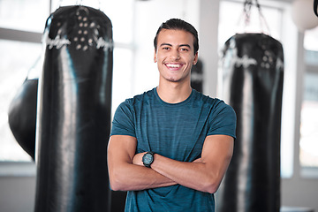 Image showing Portrait, boxing and punching bag with a man in the gym, standing arms crossed for fitness or motivation. Happy, exercise and confidence with a handsome young male boxer training for a fight