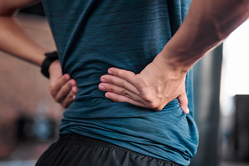 Image showing Hands, back and injury with a sports man holding a muscle in pain while training in a gym for health. Fitness, accident and anatomy with a male athlete suffering from an injured body during exercise