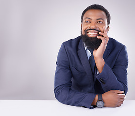 Image showing Happy, thinking and a black man sitting by a table isolated on a white background in a studio. Smile, thoughtful and an African businessman with an idea, thought or contemplation on a backdrop