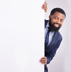 Image showing Hiding, portrait and a black man standing by a wall isolated on a white background in a studio. Mockup, happy and an African corporate employee looking from a corner with space for advertising