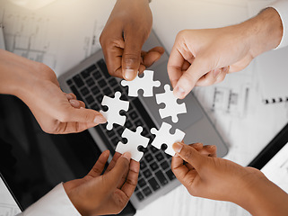 Image showing Hands, puzzle and overhead with a business team in the office, working in collaboration on a project. Teamwork, jigsaw piece and laptop with a diverse group of people at work together from above