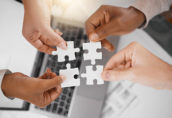 Image showing Hands, puzzle piece and overhead with a business team in the office, working in collaboration on a project. Teamwork, jigsaw and laptop with a diverse group of people at work together from above