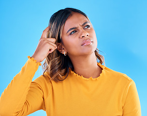 Image showing Thinking, confused and pensive woman in a studio with an idea, thoughtful or contemplating face expression. Deciding, doubtful and female model with wonder scratching head gesture by blue background.