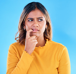 Image showing Thinking, doubt and worry with a woman on a blue background in studio feeling unsure or uncertain. Idea, confused and problem solving with a young female looking for a solution or asking a question