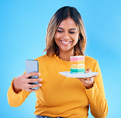 Image showing Woman, cake and studio with a selfie and smile for social media while excited to eat. Happy female on blue background with rainbow color dessert for influencer birthday celebration profile picture
