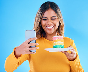 Image showing Woman, cake and smile selfie in studio for social media profile picture and excited to eat. Happy female laughing on blue background with rainbow color dessert for birthday or influencer celebration