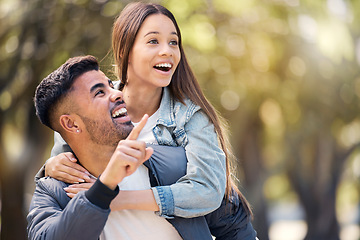 Image showing Couple, outdoor and pointing at surprise for love, care and happiness together in summer. Young man and woman at nature park for piggyback, laughing or wow at space on happy date or vacation to relax