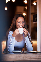 Image showing Thinking, dark and happy with a woman in a coffee shop, sitting a table while feeling during the night. Idea, smile and time with an attractive young female drinking a fresh beverage in a cafe