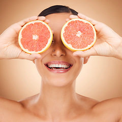 Image showing Beauty face, laugh or happy woman with grapefruit for fruit detox, healthcare or natural facial skincare routine. Vitamin c food product, fun studio or playful female nutritionist on brown background