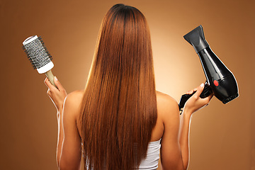 Image showing Hair, brush and hairdryer of woman in studio for growth and color shine or healthy texture. Aesthetic female hands with tools for haircare, self care and hairdresser or salon on brown background